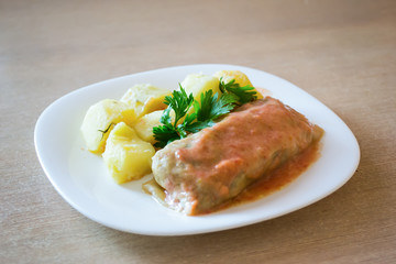 Meat-stuffed cabbage and potatoes on a plate on a table.