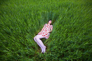 brunette in a bright dress lying in the tall grass