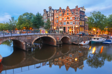 Amsterdam canal, bridge and typical houses, boats and bicycles during morning twilight blue hour, Holland, Netherlands.