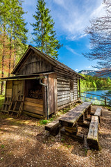 Old forest wooden hut in the Alps at the lake