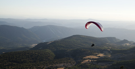 Person practicing paragliding in the air with nature background