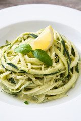 Zucchini noodles with pesto sauce on wooden table

