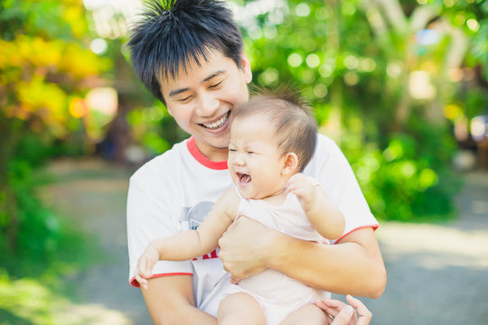 Family portrait of 9 months baby laugh and big smile with her father in the garden : Selective focus picture.