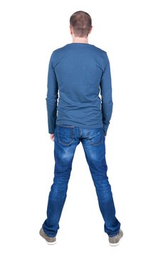 Back view of young man in t-shirt and jeans  looking. Standing young guy. Rear view people collection.  backside view of person.  Isolated over white background.