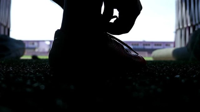Silhouette of a football player buckling his shoes before going out to the stadium