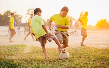 Foto op Canvas boys are playing football in the sunshine day. © nateejindakum