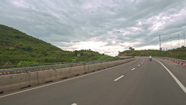Scooters Drive Fast along Highway against Rural Landscape