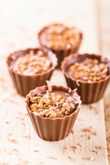 Four chocolate cupcakes with nuts and sweet shavings