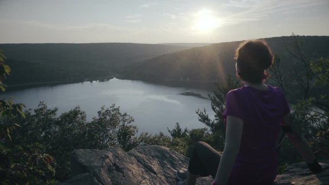 Woman seats on the mountain rocks and admiring a buatiful view