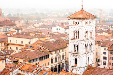Aerial cityscape view on the old town of Lucca with San Michele basilicas tower at the foggy weather in Italy