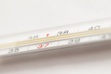 Mercury medical thermometer close-up on a neutral gray background