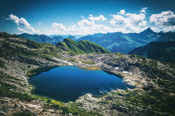Naklejka na ściany i meble Calm lake reflecting blue sky in the Alps