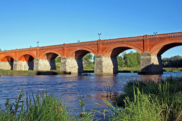 Fototapeta na wymiar Brick bridge across river Venta in Kuldiga, Latvia