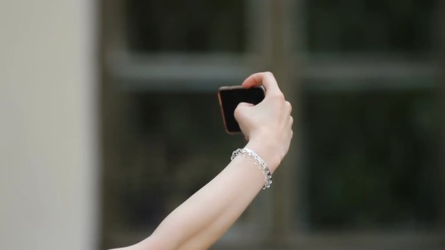 Hand of young woman taking selfie on smartphone, sharing photo in social network