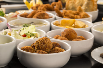 Mixed brazilian snacks, including pastries, fried chicken, salad