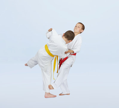 In judogi athletes are training throws on a light background