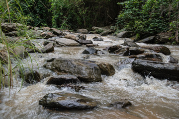 Huge active waterfall in green tropical mountain forest with peo