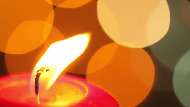 Burning Christmas candle. Flashing blurred background. Christmas decorations
