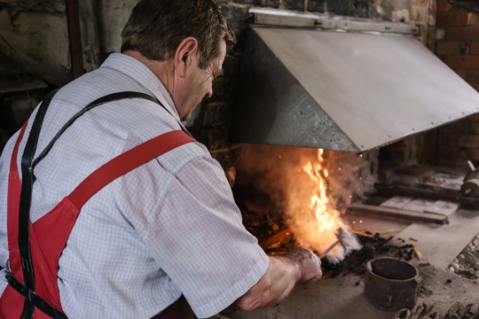 Blacksmith in workshop heating metal in furnace