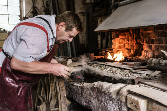 Blacksmith hardening chisel checking the glow color