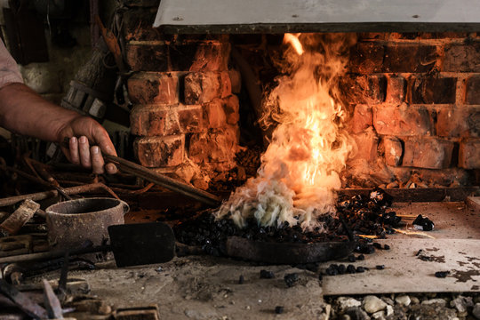 Smith heating iron in fire of his furnace