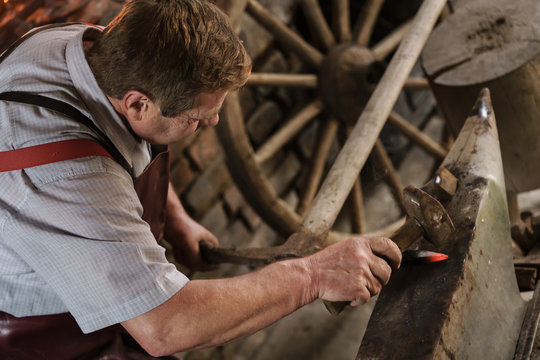 Blacksmith working on pickaxe in front of furnace