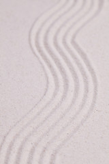 Fototapeta na wymiar Zen garden with wave pattern in the white sand
