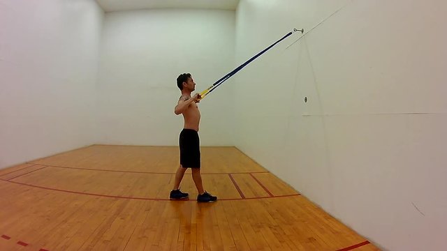 Shirtless Japanese middle age man resistance band exercise pulldown from rear view.  