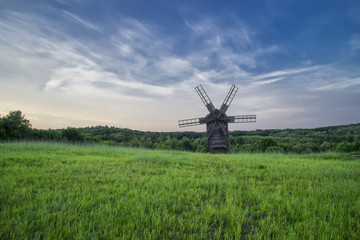 Fototapeta na wymiar Windmills in the field under the clouds at sunset in the national museum of culture and life Pirogovo, Kiev, Ukraine, Europe