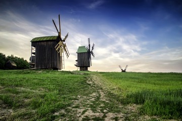 Windmills in the field under the clouds at sunset in the national museum of culture and life Pirogovo, Kiev, Ukraine, Europe