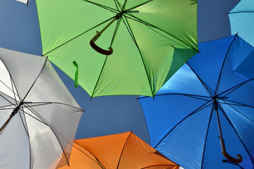 Parts of green, blue, orange and white umbrella with a part of blue sky