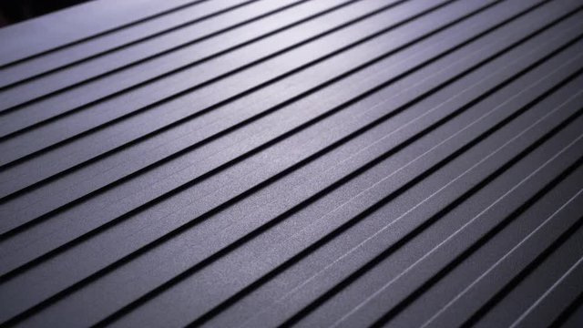 Light Shines Over Diagonally Grooved Metal and Camera Slowly Pans to Left, Macro