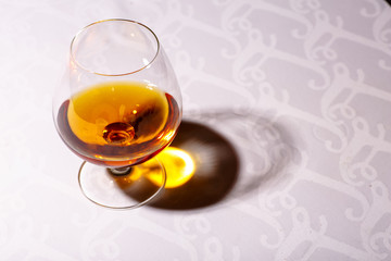 The glare from the glass of French brandy reflected on white tab
