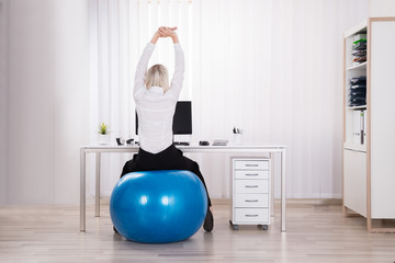 Rear View Of Businesswoman Stretching Her Arms