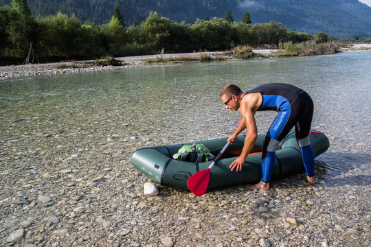 Sporty man in wetsuit, packraft in a mountain river ready to go