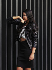 Portrait of young beautiful curvy woman plus size in striped top and black skirt over vertical striped background