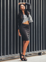 Portrait of young beautiful curvy woman plus size in striped top and black skirt over vertical striped background