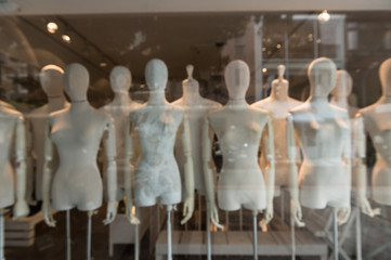 De focused/Blur image of boutique window with dressed mannequins. Boutique display window with mannequins in fashionable dresses. Toned image.
