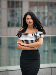 Portrait of young beautiful curvy woman plus size in striped top and black skirt over blurred city background