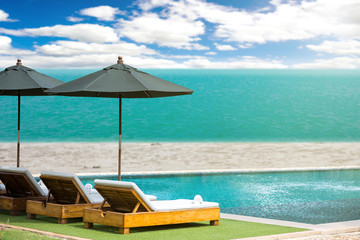 Fototapeta na wymiar Blurred blue sea and white sand beach with parasol, beach chair