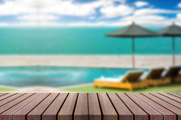 Wood table top on blur beach background with beach chairs and pa