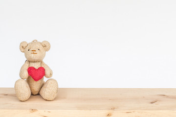 Teddy bear holding heart on wood table isolated on white background, Love concept.