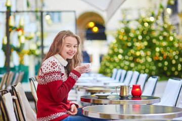 Young woman on a street of Paris decorated for Christmas