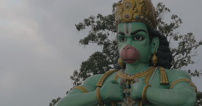 Seen head with hands of statue of Hanuman at Batu Caves, Malaysia. It is raining. Hindu landmark