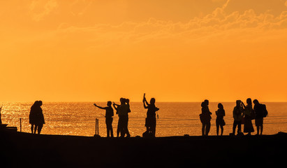 Silhouettes of people at sunset on the beach of Tanah Lot, Bali,