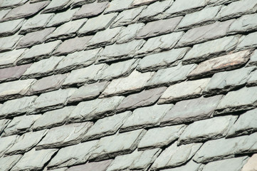 Old grey stone tiles on old vintage house roof as background