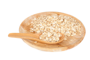 dish and wood spoon with oats flakes pile