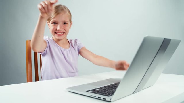 Crazy child girl something typing in laptop and laughing. Thumbs up. Ok