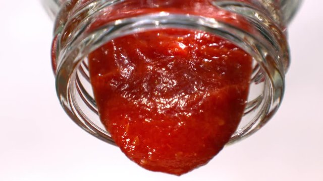 Ketchup or Red Sauce is Pouring out from a Glass Bottle Macro in Slow Motion White Background Tabletop 1080