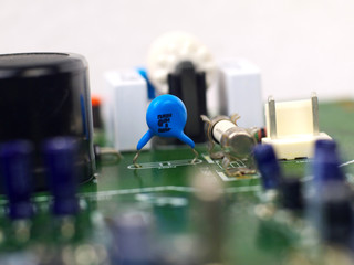 blue ceramic disc capacitor mounted on printed circuit board, shallow depth of field